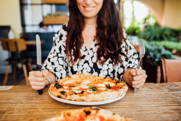 istock Woman eating pizza at cafe 1338755808