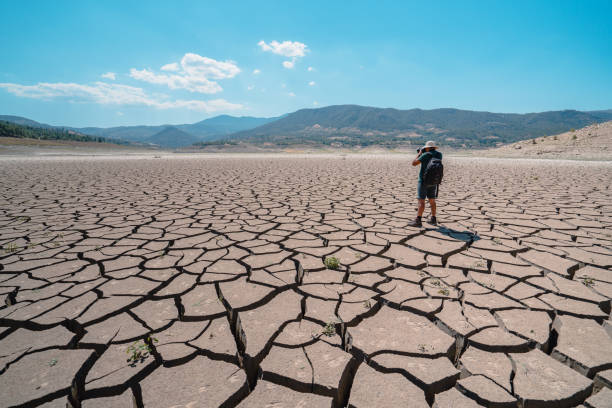 istock Photographer is taking photos on dried cracked drought lakebed surface 1338755853