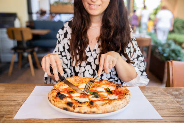 istock Woman eating pizza at cafe 1338755881