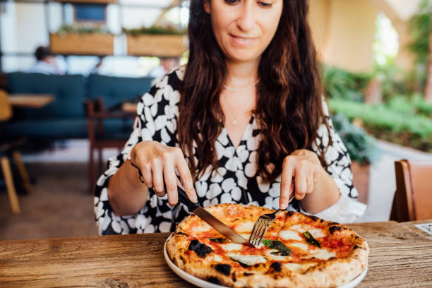 женщина ест пиццу в кафе - italian culture women looking at camera cheerful стоковые фото и изображения