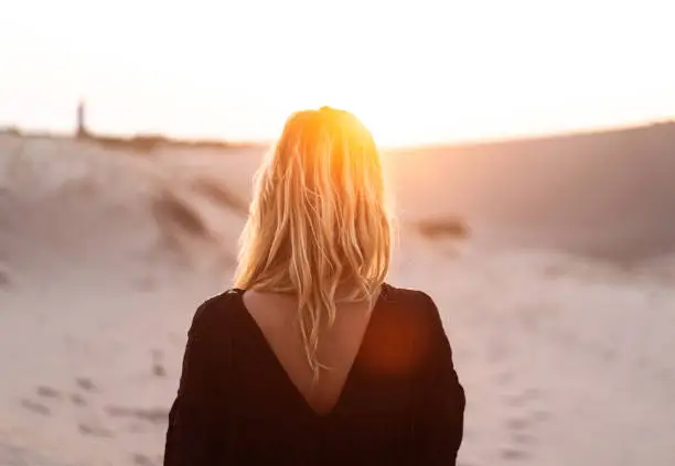 Photo of rear view of blonde beautiful woman at sunset or sunrise
