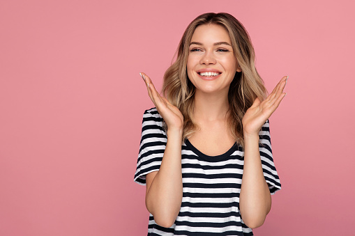 Portrait of surprised woman with open mouth hands gesturing looking aside to copy space for advertisement. Excited positive young female shout from surprise and excitement over pink studio background