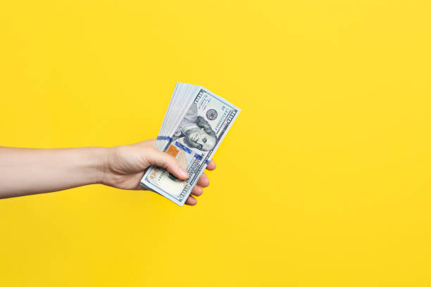 istock Hand holding a big stack of banknotes isolated on yellow background. Wealth or loan concept. Banner with copy space 1338757753