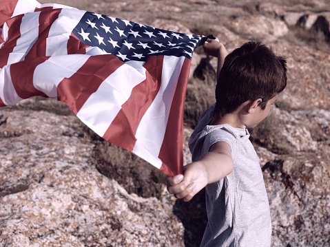 A boy holding waving american US flag, patriotism concept.