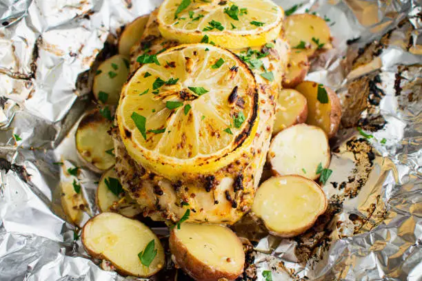 Chicken breast and potatoes roasted in a foil packet and topped with sliced lemons