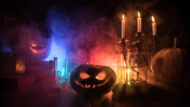 Halloween still-life background with different elements on dark toned foggy background. Selective focus Wizard's Desk. Horror Halloween concept. Magic potions in bottles on wooden table with books and candles. Halloween still-life background with different elements on dark toned foggy background. Selective focus alchemy photos stock pictures, royalty-free photos & images