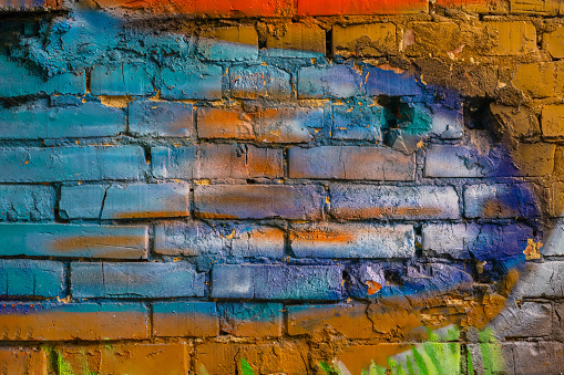 Rough plastered brick wall with cracks. Paint splash, colorful background, texture, copy space