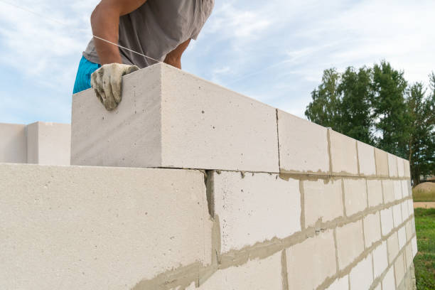 istock Builder builds a concrete wall made of cement blocks on the construction site of a residential building with his own hands. Concept of building a house 1338762424
