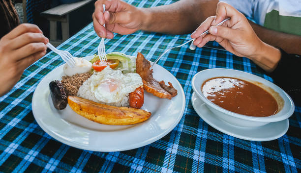 un groupe de personnes mange la célèbre bandeja paisa - bandeja paisa photos et images de collection