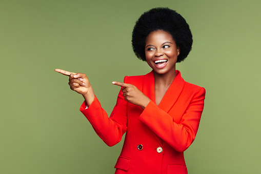 Alegre mujer de negocios negra señala con el dedo alegre indicar espacio para la promoción o los anuncios que se muestran a la derecha photo