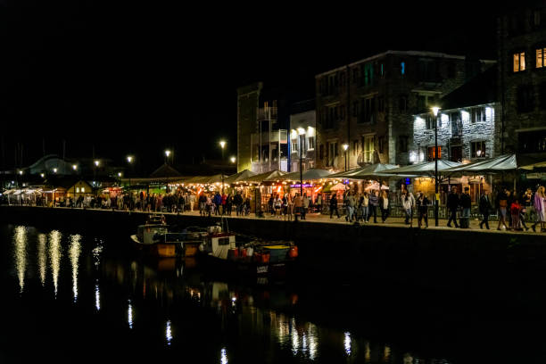Plymouth, UK. Wednesday 18 August 2021. People walk past bars and restaurants in Plymouth's Sutton harbour.
