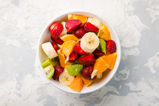 fruit salad with banana, strawberry, orange and kiwi top view
