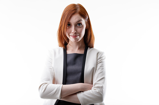 Smiling woman raising her eyebrow at the camera with a sceptical or disbelieving look as she poses with folded arms isolated on a white background