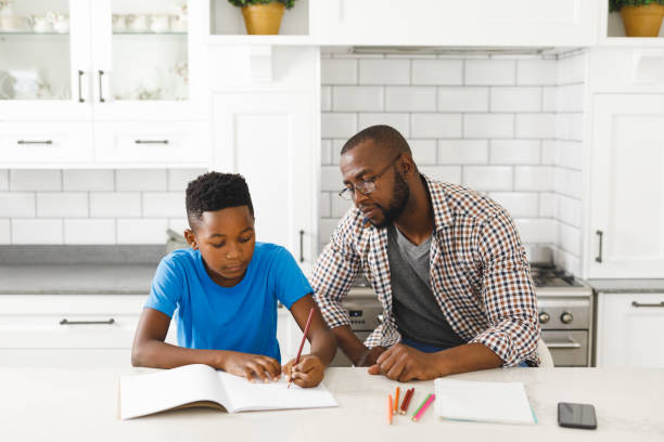 istock African american father and son in kitchen, doing homework together 1338772010