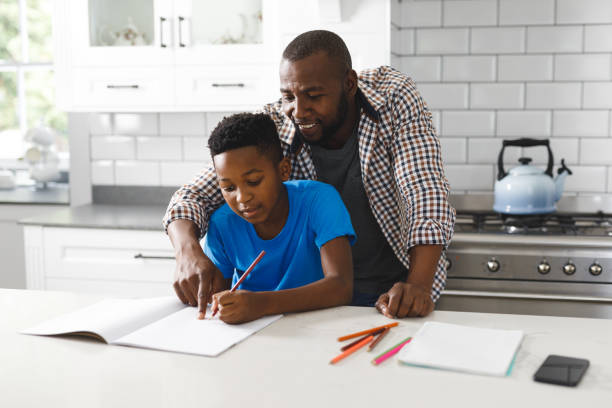 istock Smiling african american father and his son in kitchen, doing homework together 1338773619