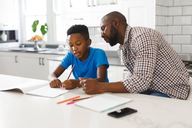 istock African american father and son in kitchen, doing homework together 1338774427