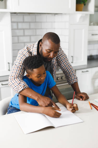 istock African american father and his son in kitchen, doing homework together 1338774446