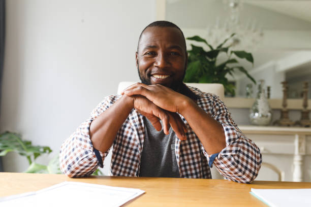 istock Smiling african american man sitting at table in dining room, making video call 1338774565