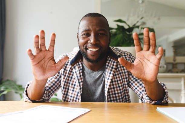 istock Smiling african american man sitting at table gesturing in dining room, making video call 1338775322