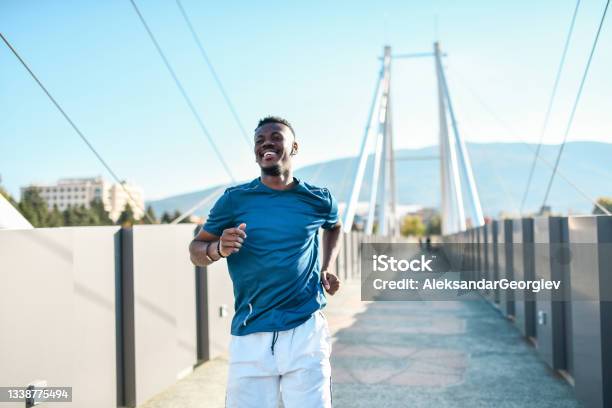 Smiling African Male Testing His Endurance Capabilities While Running On Bridge Outside