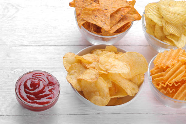 différents types de chips dans des bols et de la sauce rouge sur une table en bois blanc. - acute pain photos et images de collection