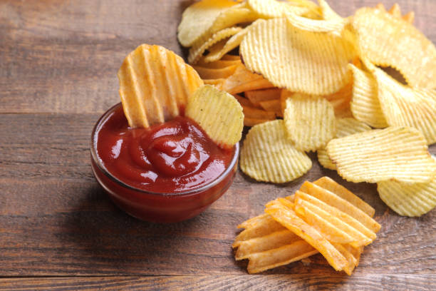 beaucoup de chips différentes avec de la sauce rouge sur une table en bois brun. collations. - acute pain photos et images de collection