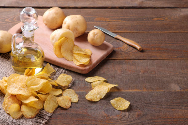 chips au beurre et pommes de terre fraîches sur une table en bois brun. ingrédients - acute pain photos et images de collection