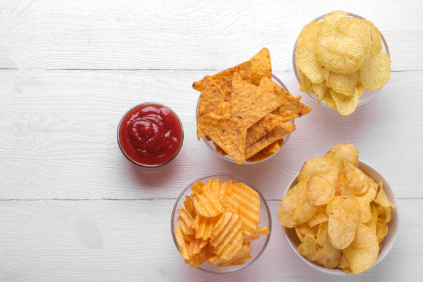 différents types de chips dans des bols et de la sauce rouge sur une table en bois blanc. vue d’en haut - acute pain photos et images de collection