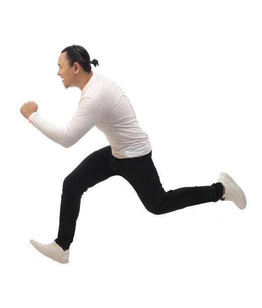 Man wearing casual grey shirt black denim and white shoes, running forward, moving with confidence, side view. Full body portrait isolated stock photo