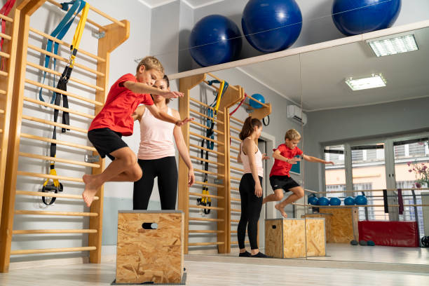 energiegeladenes kind springt auf holzkiste im fitnessstudio - kletterwand turngerät stock-fotos und bilder