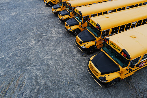 Aerial view of school buses stored in a gravel lot on a weekend.