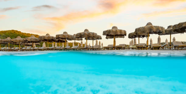 istock (Selective focus) Split shot, over under picture. Crystal clear, turquoise water and some beach umbrellas illuminated during a stunning sunrise. Grande Pevero Beach, Sardinia, Italy. 1338794074