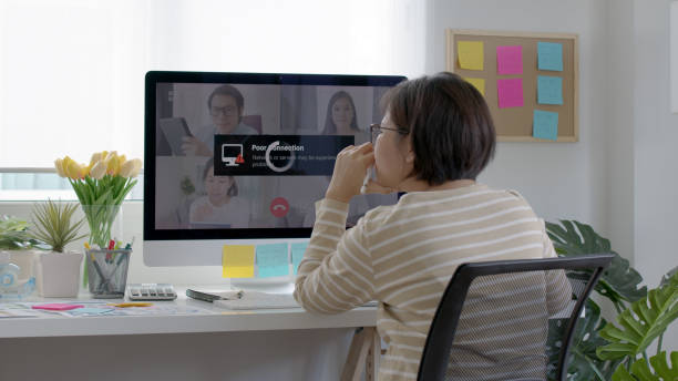 バックビュー成熟した中年アジアの女性従業員は、自宅でコンピュータデスクトップpcビデオコールウェビナー会議怒っている低貧しい信頼性の低い悪い無線lan接続の遅い問題停止から仕事� - low back ストックフォトと画像