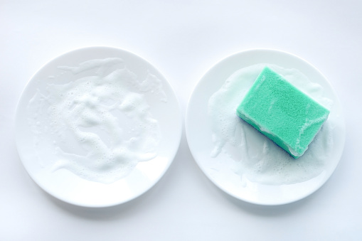 White soapy plates and a sponge for washing dishes.