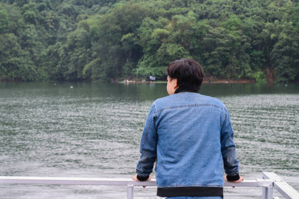 istock young man wearing jacket relaxing by the lake 1338803373