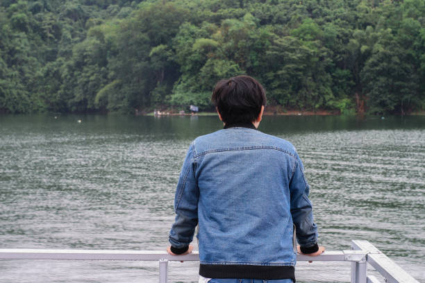 istock young man wearing jacket relaxing by the lake 1338803380