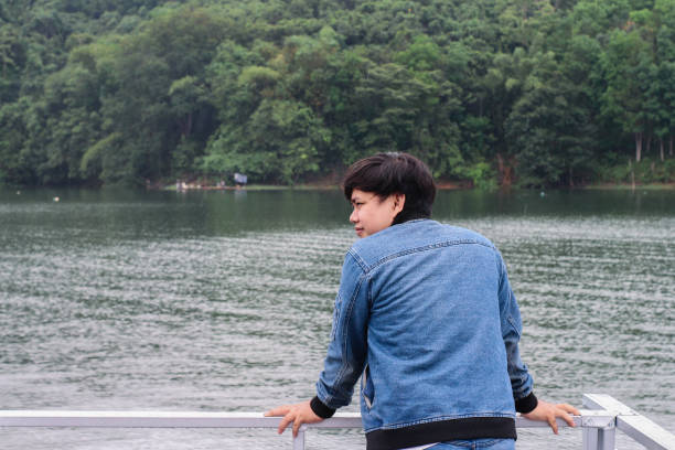 istock young man wearing jacket relaxing by the lake 1338803424