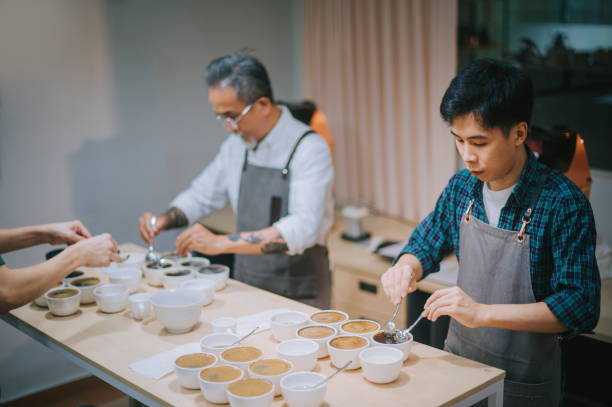 istock male Asian Chinese barista scooping skimming coffee grounds during coffee cupping scoping with 2 spoon 1338803479