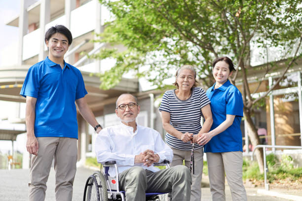 anziani e badanti su sedia a rotelle - nursing home senior adult group of people home caregiver foto e immagini stock