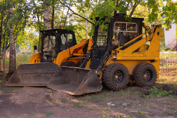 istock Two mini loaders with a bucket stand in the shade of a tree 1338805256