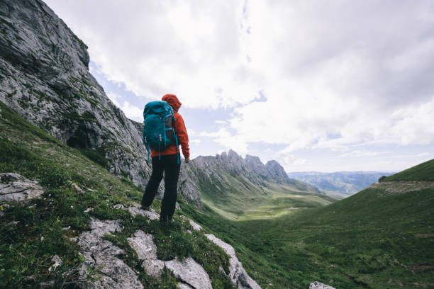 istock Successful woman hiking on sunset alpine mountain peak 1338806045
