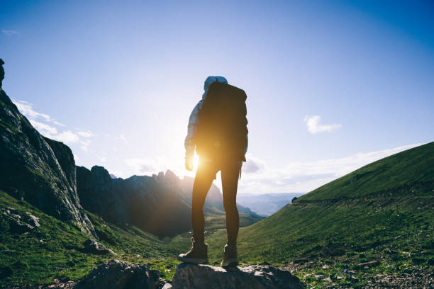 istock Successful woman backpacker hiking on sunset alpine mountain peak 1338806186