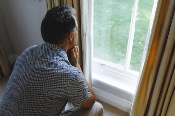istock Thoughtful senior caucasian man sitting on sofa and looking through window 1338807052