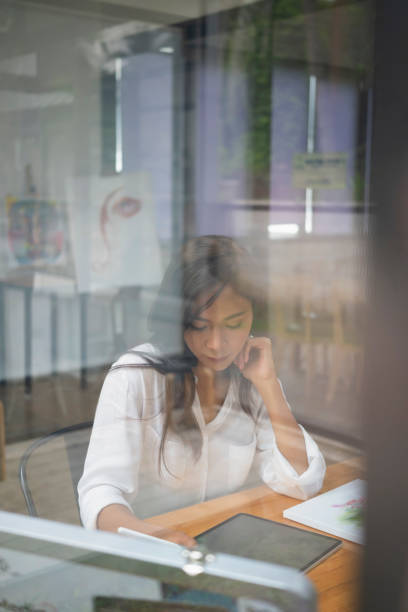 istock View through glass window creative designer woman working in her art studio. 1338807216