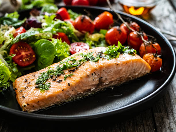 bistecca di salmone fritta, patate arrosto e verdure fresche su fondo di legno - salmone arrosto foto e immagini stock