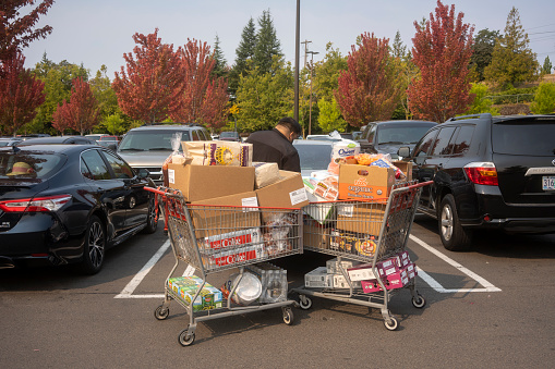 Tigard, OR, USA - Sep 3, 2021: A masked customer loads his car after shopping in Costco in Tigard, Oregon, amid the COVID pandemic.