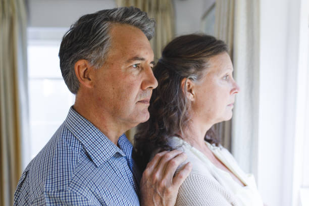 istock Thoughtful senior caucasian couple standing next to window, embracing 1338810068