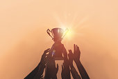 People with gold trophy cup on color background, closeup