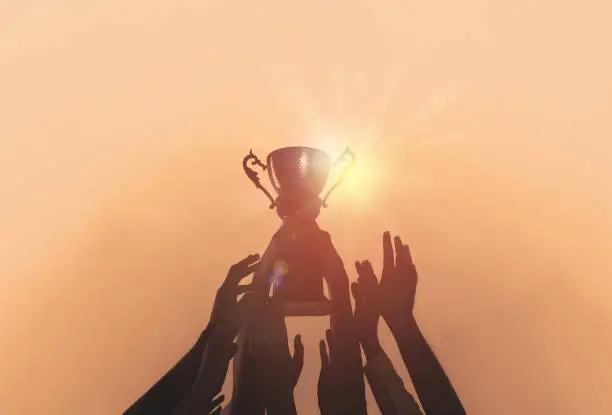 Photo of People with gold trophy cup on color background, closeup