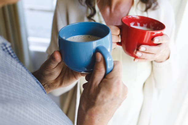istock Senior caucasian couple standing next to window, holding cups 1338811299